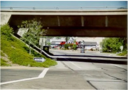 View from beneath the Interstate 5 overpass looking toward Main Street in Yreka, showing the concrete bridge structure overhead and the road descending toward commercial buildings visible beyond the underpass