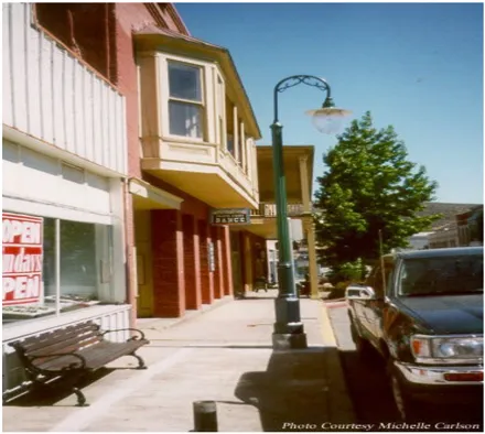 Historic commercial buildings along Miner Street in Yreka featuring colorful facades, a decorative street lamp with a globe light, a park bench on the sidewalk, and a street sign. The buildings showcase the architectural character of the Historic District. Photo courtesy Michelle Carlson.