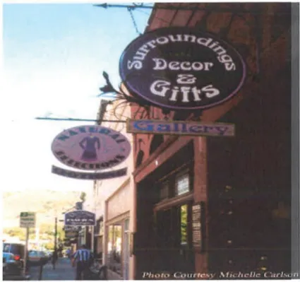 Storefront signs along Miner Street in Yreka’s Historic District, including hanging signs for “Surroundings Decor &amp; Gifts” and “Natural Selections Gallery.” The historic commercial buildings feature traditional facades and a sidewalk-level shopping atmosphere. Photo courtesy Michelle Carlson.